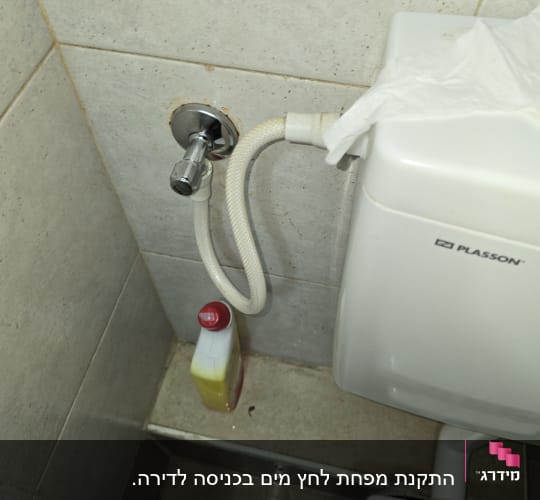 אסלה עם צינור מים ובקבוק חומר ניקוי